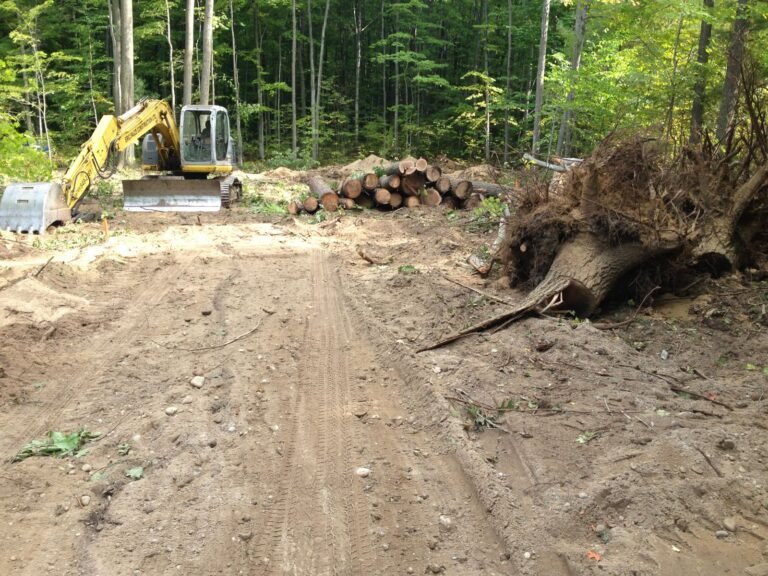 Excavator pulling stumps while clearing a building lot